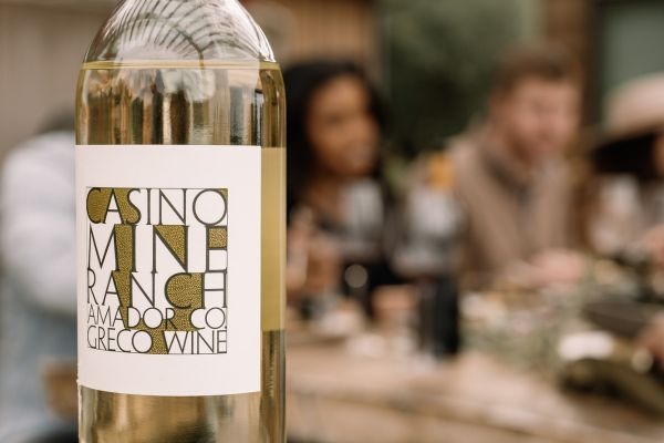 Casino Mine Ranch Greco wine bottle with people blurred out in the background.