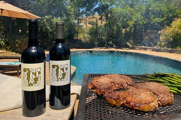 Casino Mine Ranch wine bottles of Zinfandel and Tempranillo poolside with a grill cooking meat and asparagus.
